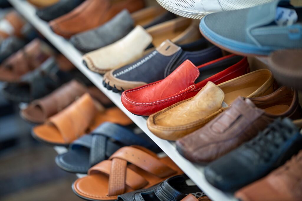 A variety of colorful leather shoes neatly arranged on a store display shelf.